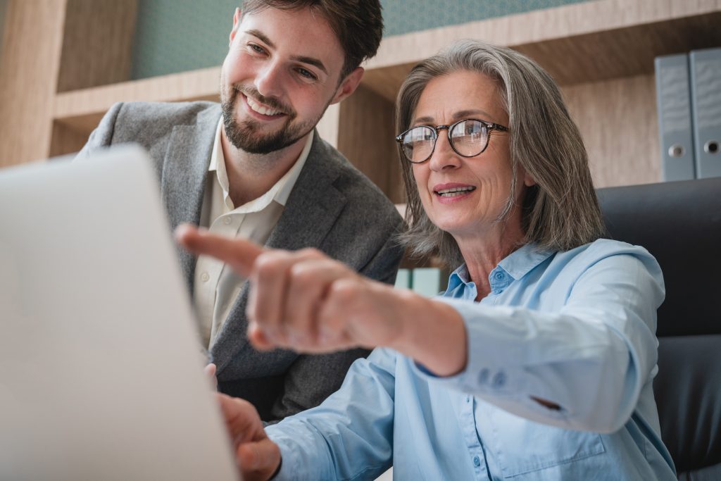 Professional Collaboration Between Mature Woman and Young Man at Office Desk