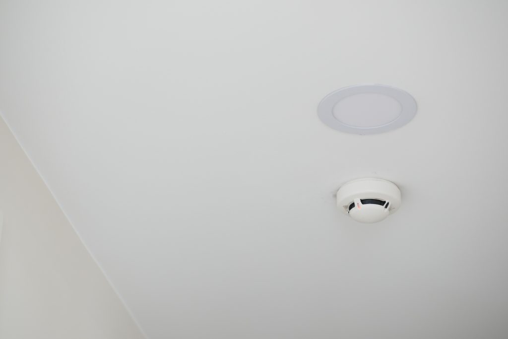 White smoke detector on ceiling at home
